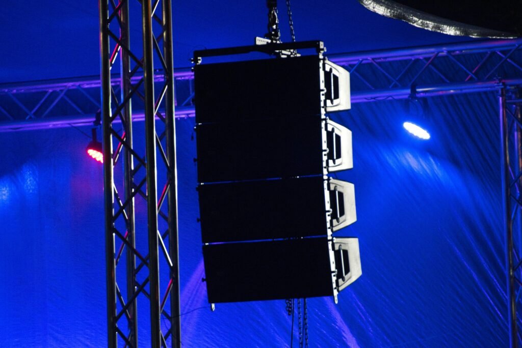 A loud speaker hung in an arena in blue lighting